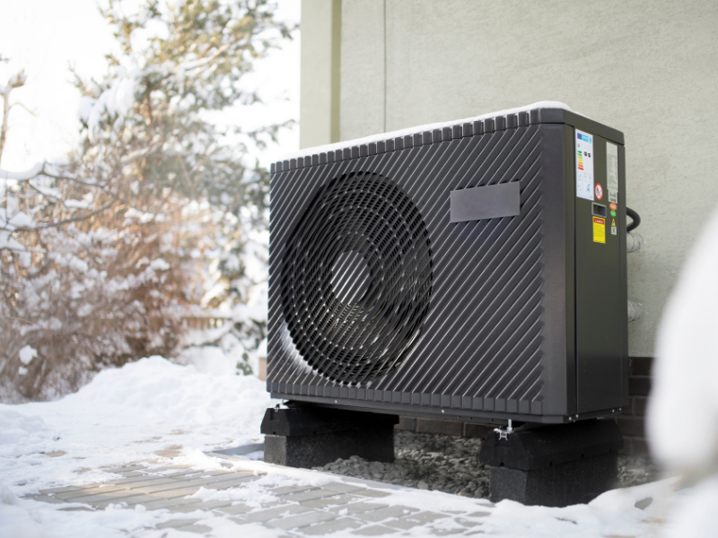 A heat pump located outside next to a building,