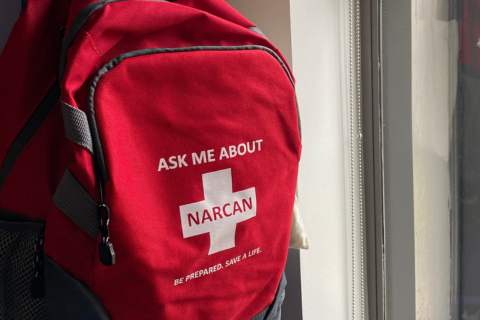 Red backpack with white text, Ask me about Narcan.
