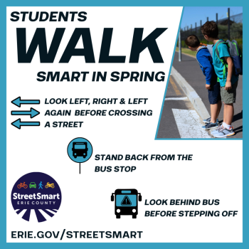 Two children wearing shorts and backpacks stand at the end of a road, looking away from the camera.