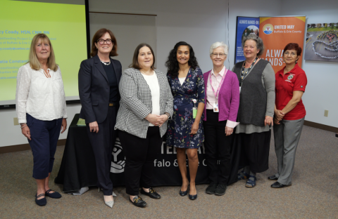Seven women standing in a classroom setting at the United Way after a panel discussion about breastfeeding, chestfeeding and lactation in the workplace.
