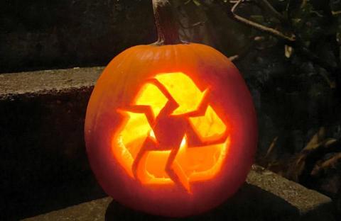 An image of a jack-o-lantern with a recycling symbol carved into it.